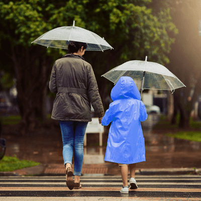 Mother and daughter holding umbrellas while crossing road